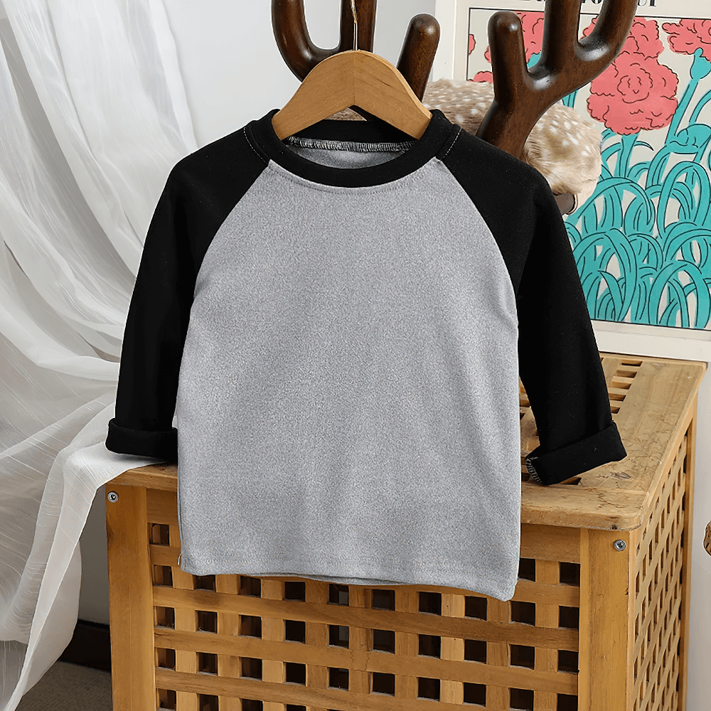 Cute kid's raglan sleeve top in black and gray with a round neck, perfect for stylish little ones. Displayed on a wooden hanger.